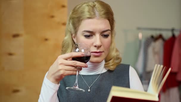 Relajada mujer leyendo libro y bebiendo una copa de vino tinto, disfrutando del ocio — Vídeos de Stock