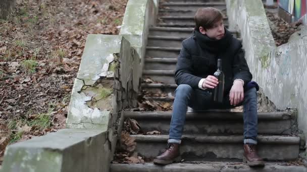 Drunk guy sitting on abandoned stairs in park with bottle in hand, alcoholism — Stock Video