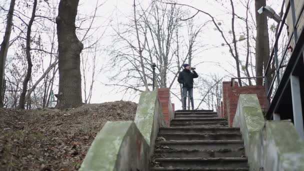 Junger Mann verschwendet Jugend, während er Alkohol trinkt, irrt durch verlassenen Park — Stockvideo