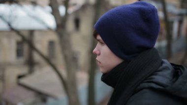 Tek başına oturmak, kameraya bakarak üzgün evsiz genç sosyal reklam