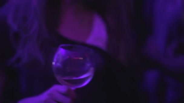 Сексуальная леди тусуется в ночном клубе с бокалом вина, наслаждаясь прохладной атмосферой — стоковое видео