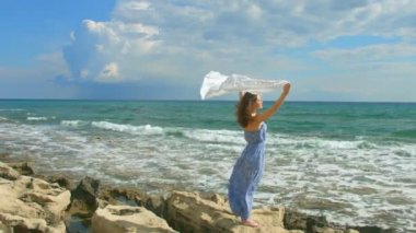 Sahil, beyaz kaşkollu rüzgarda sallayarak üzerinde duran kadın. Özgürlüğün sembolü