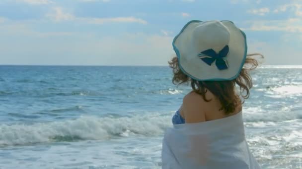 Woman wrapped in white scarf looking at beautiful ocean waves, early autumn — Stock Video