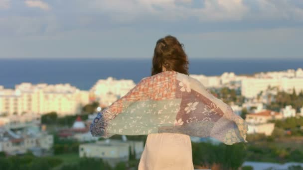 Mujer disfrutando de la brisa del mar en la colina, mirando a la ciudad costera. Sensación de libertad — Vídeos de Stock