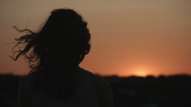 Mörk siluett av kvinna titta på solnedgången, sunrise. Hår vajande i vinden. Mysterium — Stockvideo
