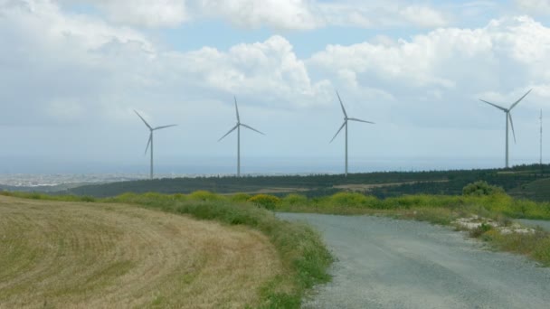 Estrada abandonada perto de moinhos de vento modernos que giram no parque eólico. Tecnologia futura — Vídeo de Stock