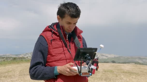 Camarógrafo profesional que controla el vuelo del dron, viendo la pantalla, filmando video — Vídeo de stock