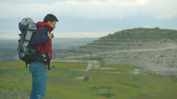 Cara decolando mochila pesada, respirando ar fresco, desfrutando de paisagem incrível — Vídeo de Stock