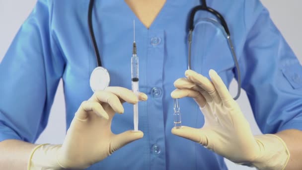 Врач держит в руках вакцину и шприц, рекламирует новые лекарства — стоковое видео
