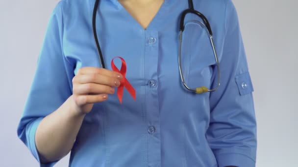 Ginecologista segurando fita vermelha e preservativo, conscientização da AIDS, advertência sobre IST — Vídeo de Stock