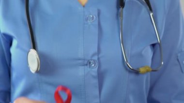 Doktor gösterilen kırmızı kurdele ve prezervatif, Uluslararası AIDS bilinçlendirme sembolü