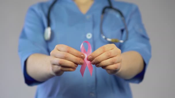 Mujer con abrigo azul sosteniendo cinta rosa en las manos y advirtiendo sobre el cáncer de mama — Vídeos de Stock