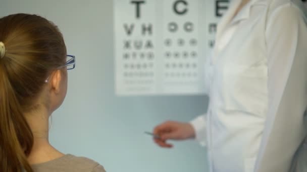 Augenuntersuchung: Mädchen setzt Brille auf, um Augenlicht beim Augenarzt zu überprüfen — Stockvideo