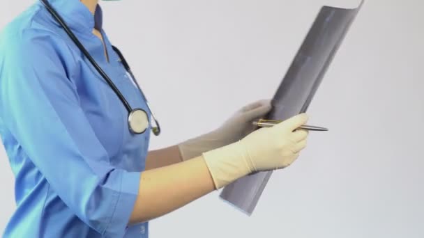 Профессиональный хирург смотрит на рентген шеи, ставит диагноз, лечит пациента — стоковое видео