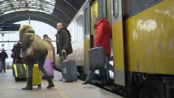 ПЕЧГУЕ, ЧЕШСКАЯ РЕСПУБЛИКА - CIRCA DECEMA, 2015: Пассажиры на вокзале. Многие пассажиры с чемоданами покидают поезд и идут по железнодорожной платформе — стоковое видео