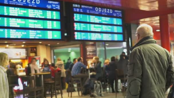 Cafetaria in de wachtkamer, oude man met bril kijken naar trein schema — Stockvideo