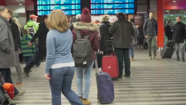 PRAGUE, CZECH REPUBLIC - CIRCA DECEMBER, 2015: Penumpang di stasiun kereta api. Wanita muda melihat jadwal kereta api di ruang tunggu, pariwisata. Lambat-gerak — Stok Video