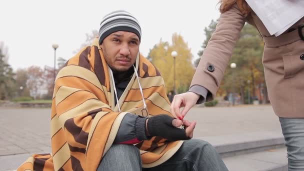 Беспомощный мужчина, сидящий один на городской улице, просящий о помощи, женщина, дающая милостыню — стоковое видео