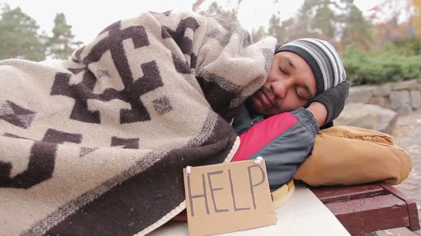 Smutný bezdomovec trpí studené, spaní na lavici pokryté přikrývky — Stock video
