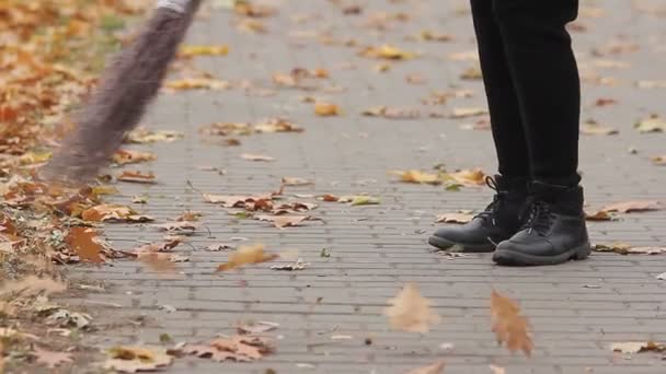 Voeten van straat cleaner vegen herfst park, iemand die hard werkt voor lage lonen — Stockvideo