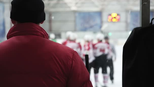 Хоккейный тренер наблюдает за началом матча между соперничающими командами, судьи на катке — стоковое видео