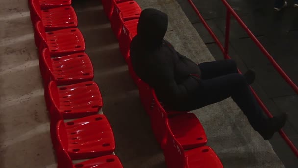 Extraño hombre con ropa negra sentado en la tribuna, mirando a su alrededor sospechosamente — Vídeos de Stock