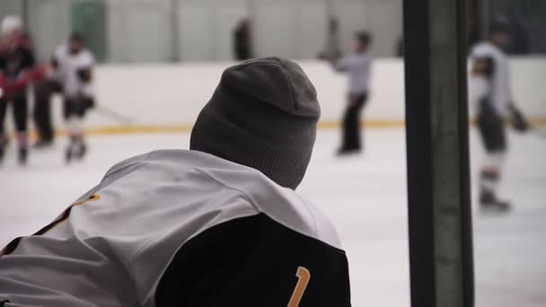 Дисквалифицированный или травмированный хоккеист смотрит матч на катке со скамейки запасных — стоковое видео