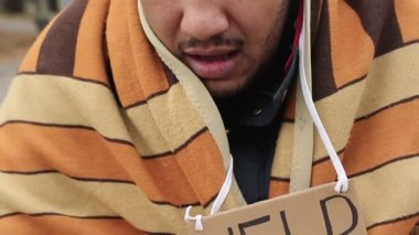 Evsiz erkek umutla kameraya, bakarak sefil yüz yalvarıyor. Yoksulluk