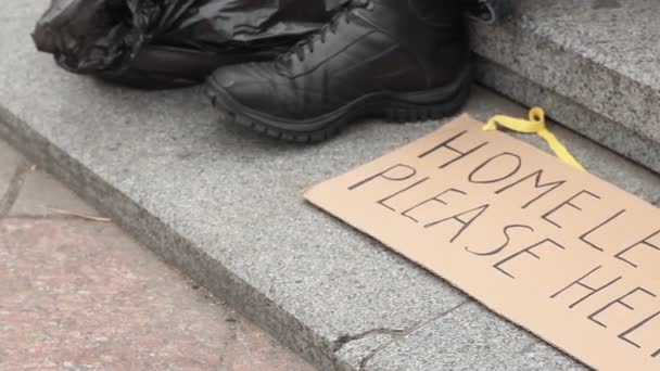 Sem-abrigo, por favor, ajude a placa de papelão deitada no chão, sem-abrigo a implorar — Vídeo de Stock