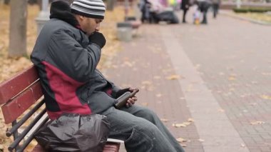 Şişe bira, alkol bağımlılığı ile tutarak yalnız sarhoş adam bankta, öksürük