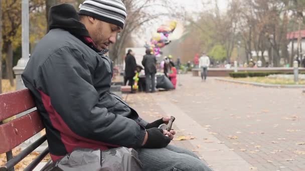 Alcohol verslaafde zittend op bankje in park met bierfles, slechte levensstijl keuzes — Stockvideo