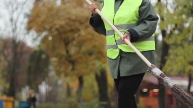 Düşen yapraklar park, düşük ücretli iş, kriz süpürme üniformalı kadın hademe