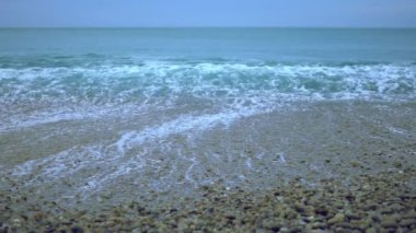 Dalga kıyıya slowmotion, çakıl plajı sisli havada haddeleme köpüklü okyanus