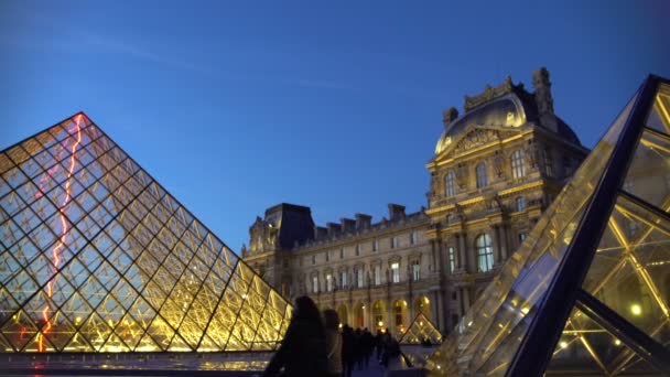 ПАРИЖ, ФРАНЦИЯ - CIRCA JANUARY 2016: Туристы собираются осмотреть достопримечательности. Посетители музея Лувр делают селфи возле стеклянных пирамид, удивительное путешествие в Париж — стоковое видео