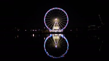 Gece cityscape ışıklı dönme dolap yansıması karanlık su yüzeyi ile