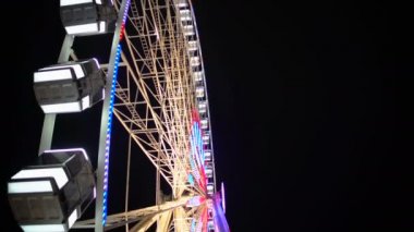 Büyük eğlence parkı karanlık gece gökyüzü altında dönen dönme yan görünüm