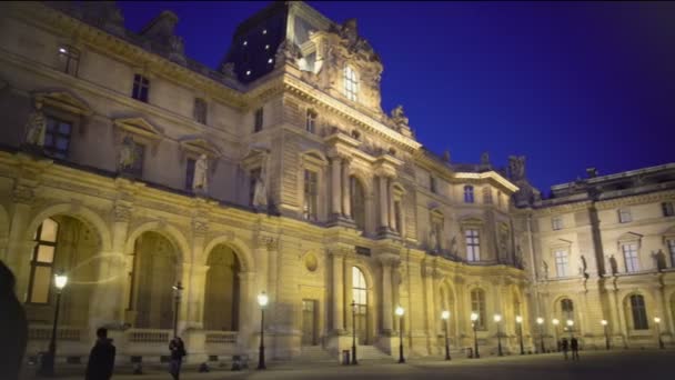 Панорама величественного дворца Лувр освещается ночью, многие туристы — стоковое видео