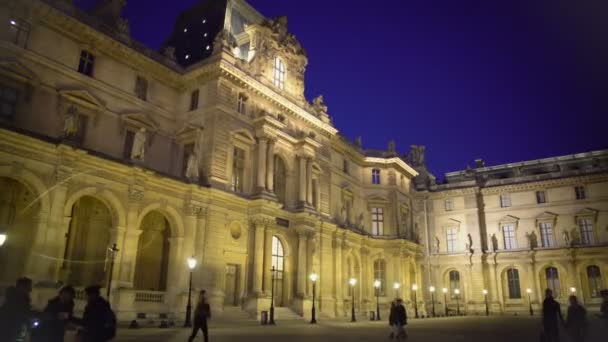 ПАРИЖ, ФРАНЦИЯ - CIRCA JANUARY 2016: Туристы собираются осмотреть достопримечательности. Многие туристы просматривают освещенный Лувр музей в Париже ночью, панорама — стоковое видео