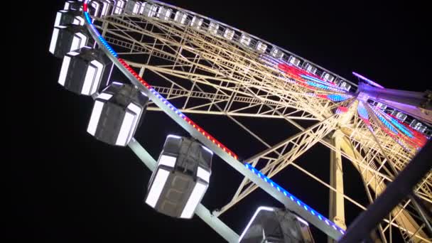 Huge Ferris wheel with illuminated passenger cars rotating fast, amusement ride — Stock Video