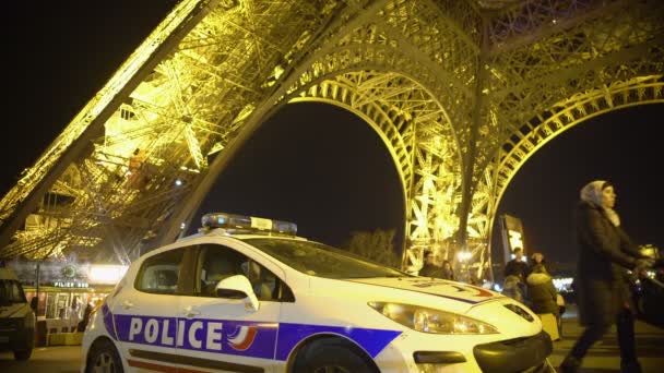 Paris, Frankrijk - Circa januari 2016: Toeristen gaan sightseeën. Politie-auto patrouilleren onderaan van de Eiffeltoren, toeristen genieten van de nacht in Parijs — Stockvideo