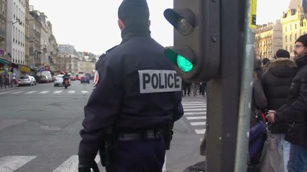 PARÍS, FRANCIA - CIRCA ENERO 2016: La gente cruza la calle. Dos policías en servicio controlando el tráfico, peatones esperando cruzar la calle — Vídeos de Stock