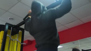 Spor salonunda, pull-up egzersiz yaparak kapüşonlu adam çok güçlü olmak için eğitim