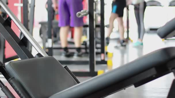 Gente activa haciendo ejercicio en el gimnasio, ejercitándose en equipos deportivos, ambiente de gimnasio — Vídeo de stock