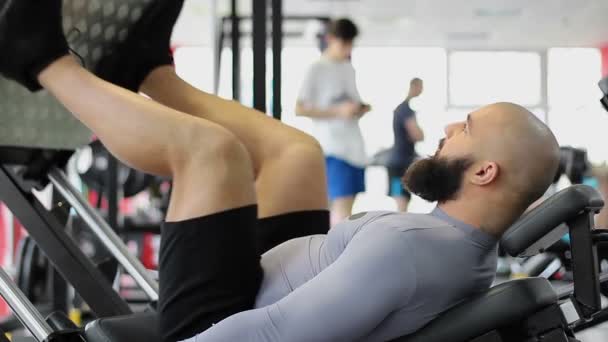 Muskulös manliga idrottare gör tryck på benträning, träna på gym — Stockvideo