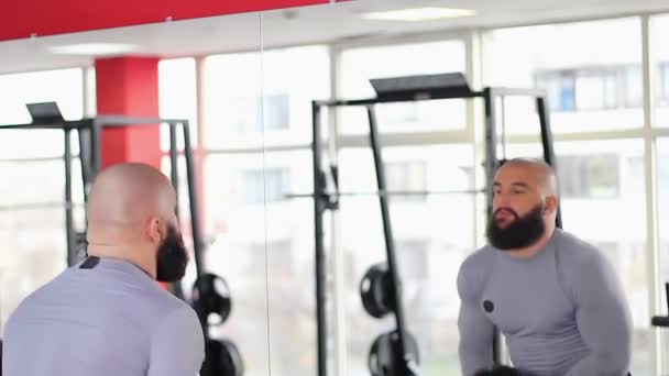 Muscular hombre haciendo tríceps extensión dumbbell ejercicio, mirando en el espejo — Vídeo de stock