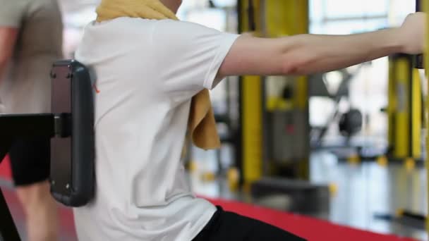Atleta principiante haciendo ejercicio en equipos deportivos en el club de fitness, primer entrenamiento — Vídeo de stock
