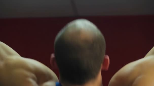 Hombros musculares masivos del culturista masculino haciendo ejercicio pull-up en el gimnasio — Vídeos de Stock