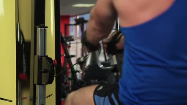Homem fisicamente forte termina fazendo exercício de linha de cabo sentado, treino ativo — Vídeo de Stock