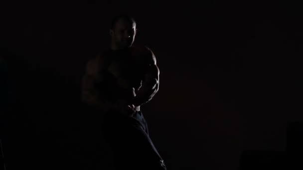 Bodybuilder professionnel fléchissant les muscles dans l'obscurité, se vantant de corps masculin — Video