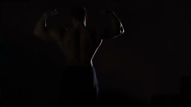 Hombre fuerte demostrando cuerpo muscular perfecto, silueta masculina en la oscuridad — Vídeo de stock